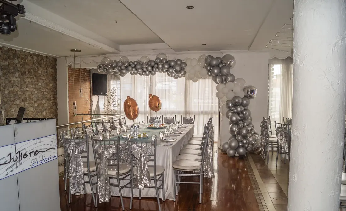 El salón de día, con piso de madera, ventanales a la calle y el letrero pintado «Juliana eventos» en el mostrador