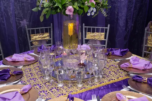 Mesa montada en morado y dorado con copas y centro floral