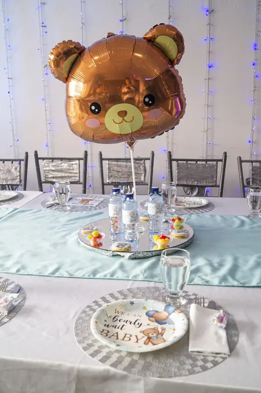 Mesa infantil en agua con globo de osito y vajilla servida