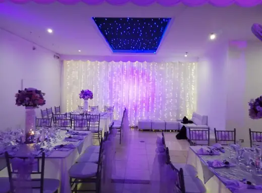 El salón completo montado con mesas largas y luz violeta
