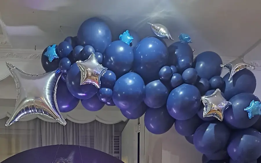 Arco de globos azul marino con estrellas plateadas montado para una ceremonia de grado