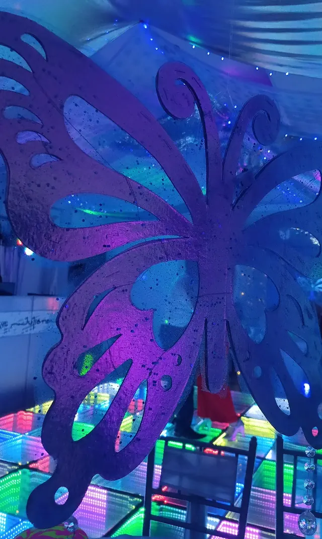 Mariposa violeta gigante colgando sobre la pista de vidrio con LEDs multicolor